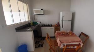 una pequeña cocina con mesa y nevera en Linda casa na cidade de Chapada dos Guimarães/MT., en Chapada dos Guimarães