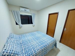 1 dormitorio con 1 cama con edredón azul y ventana en Linda casa na cidade de Chapada dos Guimarães/MT., en Chapada dos Guimarães