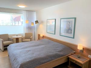a bedroom with a bed and two chairs and a window at Trafalgar 231 in Döse +9 photos