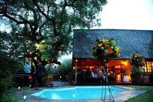 a swimming pool in front of a building with flowers on it at Needles Lodge in Marloth Park