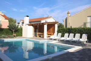 a swimming pool with chairs and a house at Villa Divine in Vodice
