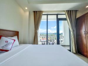 a bedroom with a large white bed and a balcony at Homestead Seaview Phú Quốc Hotel in Phu Quoc