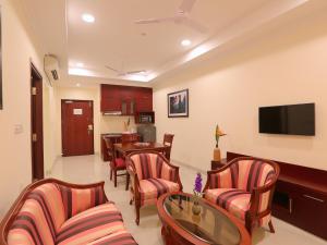 a living room with chairs and a table and a television at Lilac Hotel 3rd Block in Bangalore +19 photos