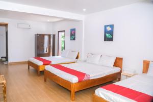 two beds in a room with white walls and wood floors at Lucky Home in Hue