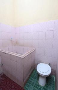 a bathroom with a toilet and a bath tub at Kost&Guesthouse Tirza in Banyuwangi