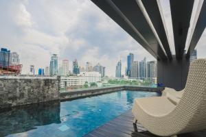 a swimming pool with two chairs and a view of a city at VOQUE Hotel & Serviced Residence Sukhumvit 51 - SHA Plus in Bangkok