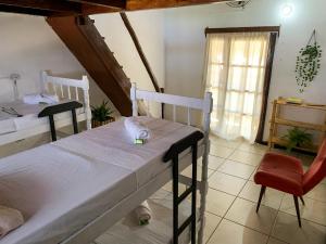 1 dormitorio con 2 camas, silla y ventana en Rudá Hostel, en Itacaré