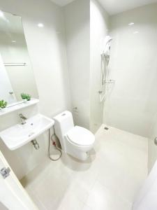 a white bathroom with a toilet and a sink at Rest Suvarnabhumi in Samutprakarn