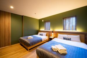 two beds in a room with green walls at Sapporo - House - Vacation STAY 88283 in Sapporo