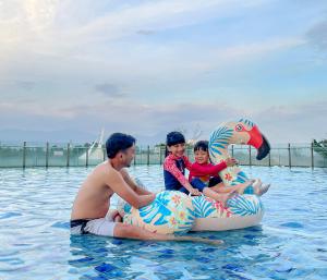 Ein Mann und zwei Kinder sitzen auf einem aufblasbaren in der Unterkunft Crowne Plaza Bandung, an IHG Hotel in Bandung