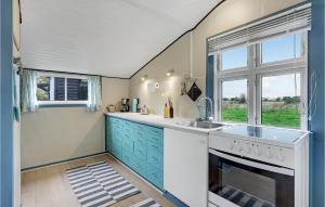 a kitchen with blue cabinets and a sink and a window at Pet Friendly Home In Nexø With Wifi in Neksø