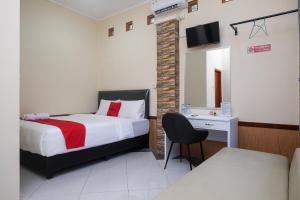 1 dormitorio con cama, escritorio y espejo en RedDoorz Syariah near Kampus UNSOED Purwokerto, en Banyumas