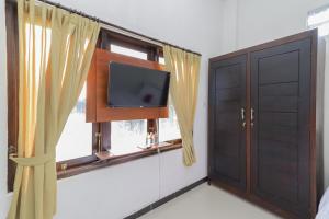 Zimmer mit einem TV und einem Fenster in der Unterkunft RedDoorz Syariah near Universitas Jember in Jember