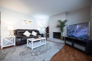uma sala de estar com um sofá de couro preto e uma televisão de ecrã plano em @ Marbella Lane - 4BR Cozy home in SJ Pool em San José