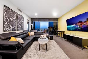 a living room with a black couch and a table at Circle on Cavill - Self Contained, Privately Managed Apartments in Gold Coast