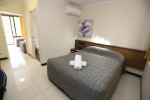 a bedroom with a bed with two white towels on it at Miners Lodge Motor Inn in Mackay