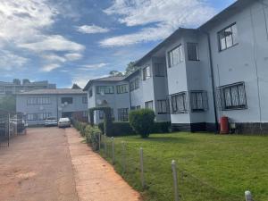 a large white building with a grass yard at @Jackie’s Avondale 2 bed flat at Harrow court in Harare