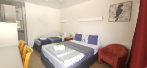 a small bedroom with two beds and a chair at Charters Towers Motel in Charters Towers