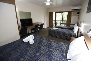 a hotel room with a bed and a desk at Miners Lodge Motor Inn in Mackay
