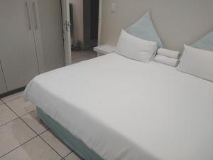 uma cama grande com lençóis brancos e almofadas em Posh 2 em Durban