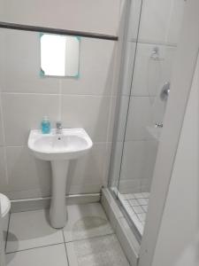 a white bathroom with a sink and a shower at Posh 2 in Durban