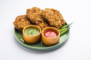 a plate of food with two dipping sauces and asparagus at Hotel green park in Jabalpur