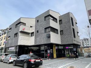 Koin Guesthouse Incheon airport في انشيون: مبنى فيه سيارات تقف امامه