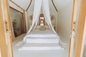 a white bed with a canopy in a room at Belajar Bali Boutique Hotel and Retreat in Canggu