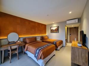 a hotel room with two beds and a desk at Parlezo by Kagum Hotels in Labuan Bajo