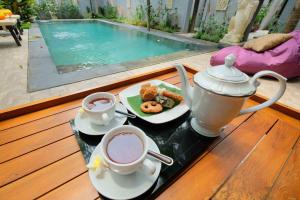 a table with two cups of tea and a plate of food at Kayangan Villas Saba in Keramas