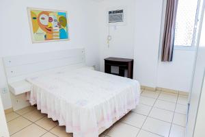 Dormitorio blanco con cama con colcha blanca en Apto c WiFi a 60m da Praia do Morro Guarapari ES, en Guarapari