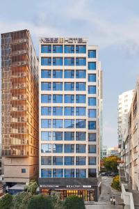 a tall white building with blue windows in a city at N285 Hotel Insadong in Seoul