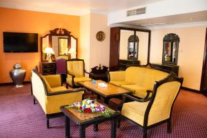فندق ديلمون انترناشونال في المنامة: غرفة معيشة بها كنب وكراسي وتلفزيون
