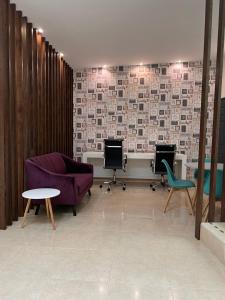 una sala de estar con un sofá púrpura y sillas en Hotel Arribo en Lagos de Moreno