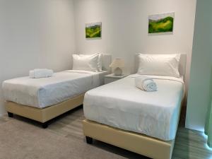 two beds in a room with white walls at Lumi Tropicana in Petaling Jaya