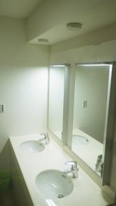 a bathroom with two sinks and two mirrors at B&B Nagomi in Tokyo