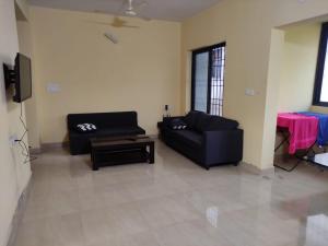 a living room with a black couch and a table at 002 MŸKA at Dsouza Heritage, Moira in Mapusa