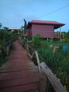 a wooden walkway leading to a red building at Happy bungalow & trekking in Banlung