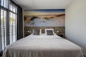 a bedroom with a large bed with a painting on the wall at Holiday Apartment Strand in Noordwijk