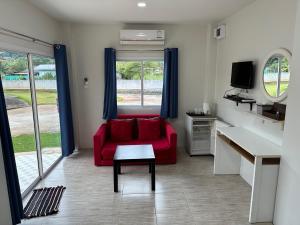 a living room with a red couch and a tv at Plearn Khaoyai Resort in Mu Si