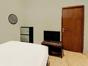 1 dormitorio con 1 cama y TV de pantalla plana en SPOT ON 91981 Diwi Homestay, en Tjakranegara