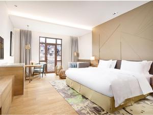 1 dormitorio con 1 cama blanca grande y escritorio en Holiday Inn Resort Zhangjiakou Chongli, an IHG Hotel en Chongli