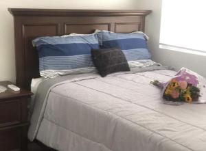 Una cama con dos almohadas y un ramo de flores. en Leona's Hidden Adventure home en Donoe