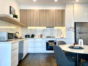 メルボルンにあるYour home on Glover St Sth Melbourne (With Parking)の白いキャビネットとテーブルと椅子のあるキッチン