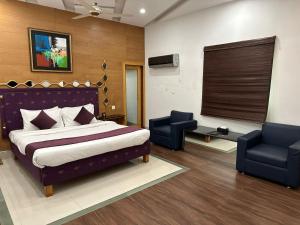 una camera con un letto e due sedie di Lawrence View Hotel a Lahore