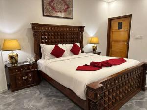 - une chambre avec un grand lit et des oreillers rouges dans l'établissement Lawrence View Hotel Lahore, à Lahore