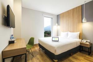 a hotel room with a bed and a desk and a television at Hotel Citradream Cirebon in Cirebon
