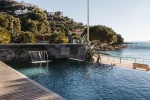a swimming pool with a waterfall and the ocean at Vista Roses Mar - Canyelles Petites Platja in Roses