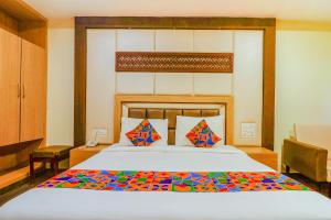a bedroom with a large bed with a wooden headboard at FabHotel Keerthi's Anupama - Nr Indira Gandhi Stadium in Vijayawāda
