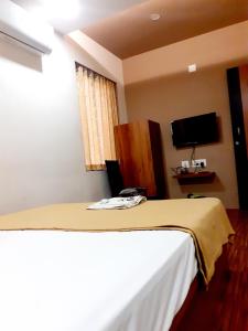 una camera da letto con un letto con una coperta gialla sopra di Hotel Madery a Mangalore